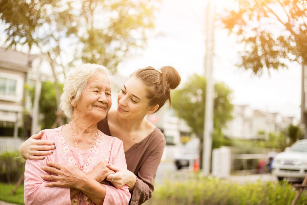 Elderly woman being embraced by caregiver daughter