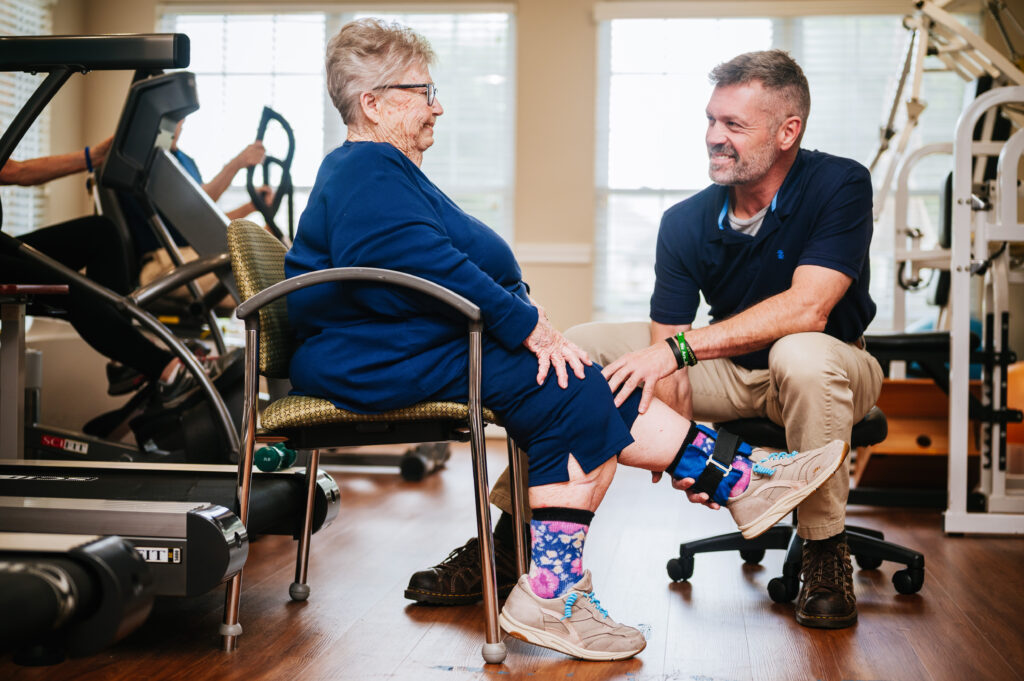 Fitness instructor helping a resident stretch while sitting down