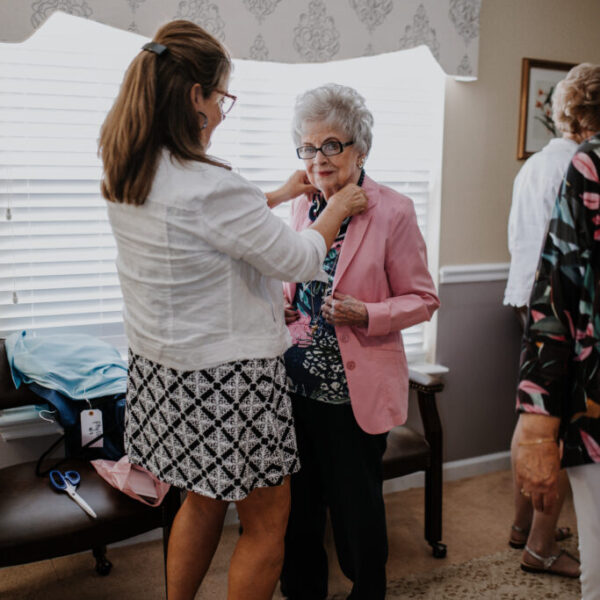 Resident trying on a blazer and a staff member is fixing the collar