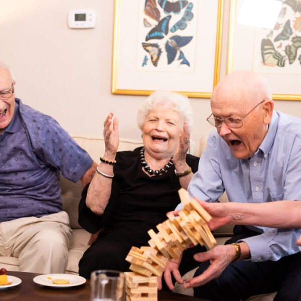 A group of seniors having refreshments and playing Jenga in a living room