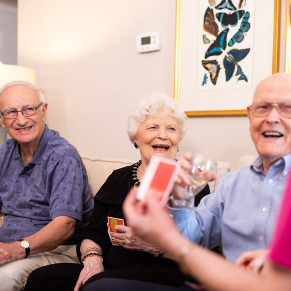 A group of seniors having refreshments and playing card games in a living room