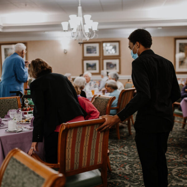 Staff member politely helping a resident into her chair