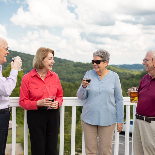 A group of seniors drinking wine and standing on the deck