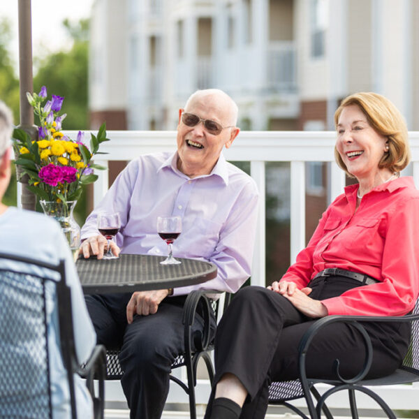 A group of seniors drinking wine and sitting on the deck