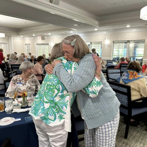 Two residents hugging each other at the Mother's Day luncehon