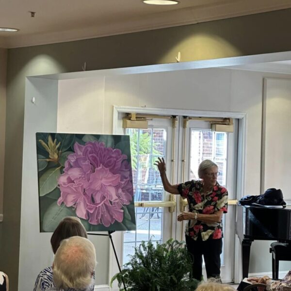 A staff member explaining the painting with flowers at the Newt and Nancy Thomas gallery