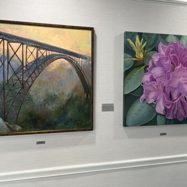 A painting of a bridge and a painting of a flower at the Newt and Nancy Thomas gallery