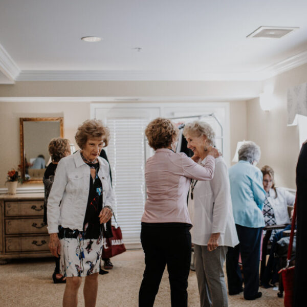 Residents helping each other try on pieces at the fashion show