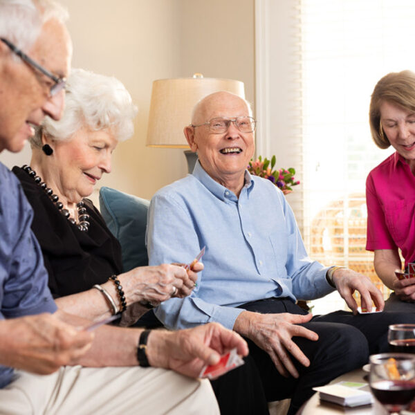 A group of seniors having refreshments and playing card games in a living room