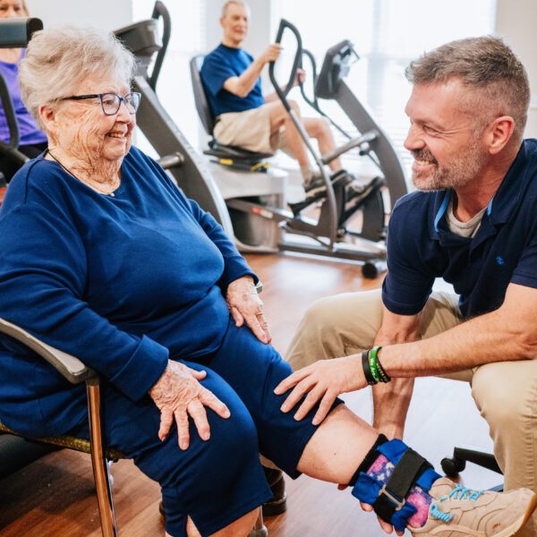 Physical therapist helping a resident stretch before working out while sitting down