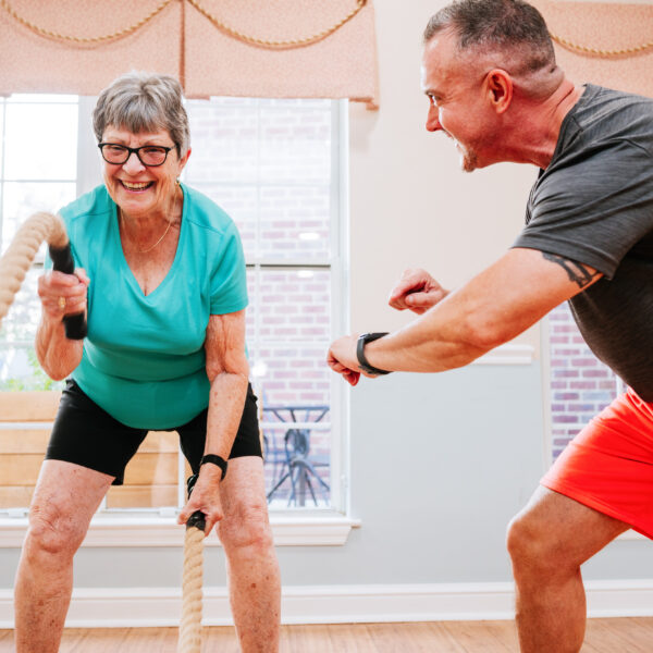 A fitness instructor helping a resident with battle ropes