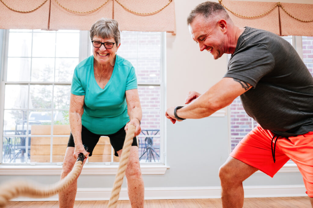 Personal trainer helping a resident with battle ropes