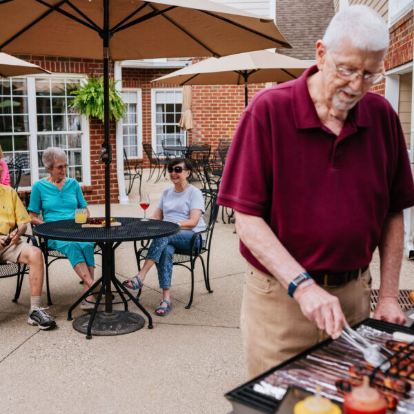 Seniors waiting for another resident to finish grilling hotdogs for the party