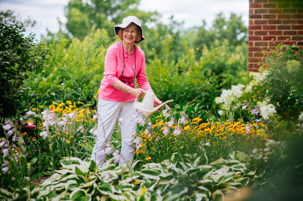 Resident watering flowers in the community garden