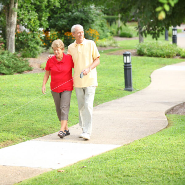 An elderly couple walking their dog in the community