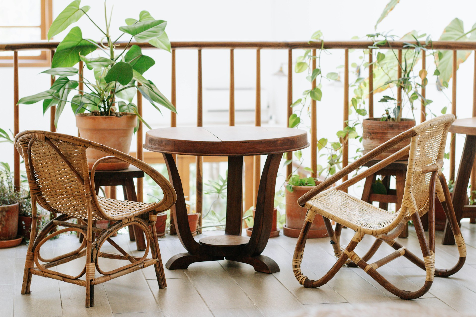 a balcony with eclectic wood furniture and potted plants